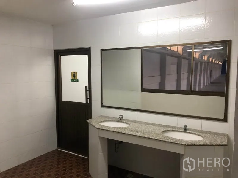 Warehouse for rent in Bang Sao Thong, Samut Prakan - Restroom area with twin sinks, a large mirror, and tiled walls.