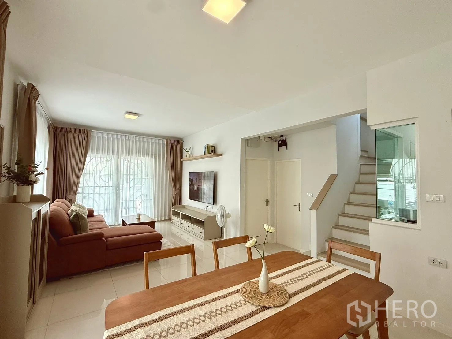 独栋房屋 for rent in Bang Phli, Samut Prakan - 开放式客餐厅，设楼梯与带窗帘的大型推拉窗。