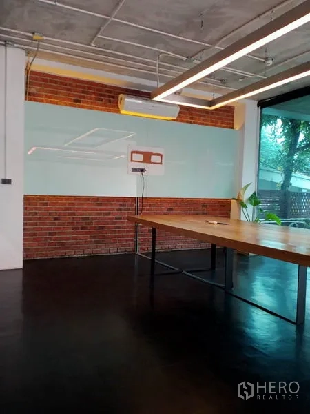 办公空间 出租在Khlong Toei, Bangkok - 会议角落，玻璃白板与木桌，临窗可见绿植景观。