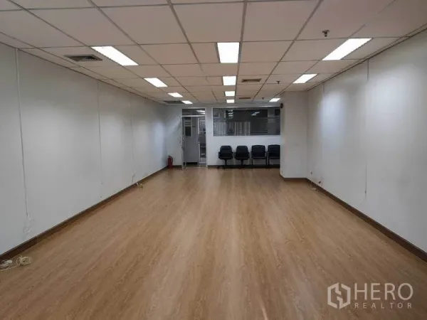 Office Space for rent in Watthana, Bangkok - Wide shot toward the entrance of an open office with laminate floors, ceiling air-conditioning, and seating by a glass partition.