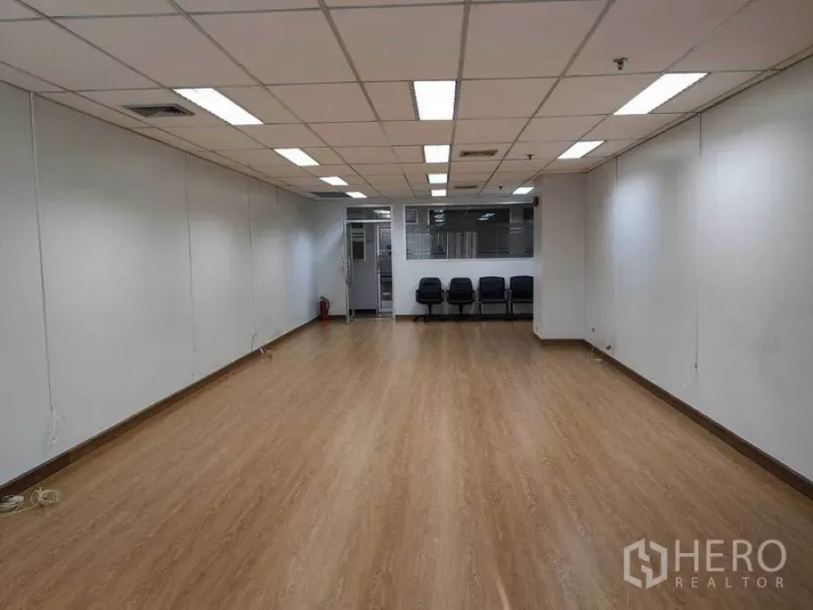 办公空间 出租在Watthana, Bangkok - 从内向外望向入口的宽敞办公室，吊顶空调、木地板及玻璃隔断旁座椅。