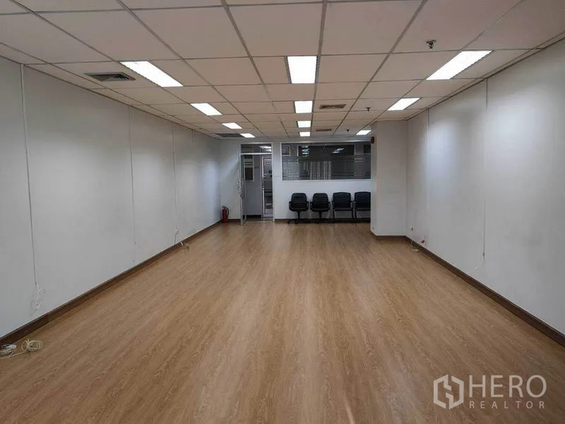 办公空间 出租在Watthana, Bangkok - 从内向外望向入口的宽敞办公室，吊顶空调、木地板及玻璃隔断旁座椅。