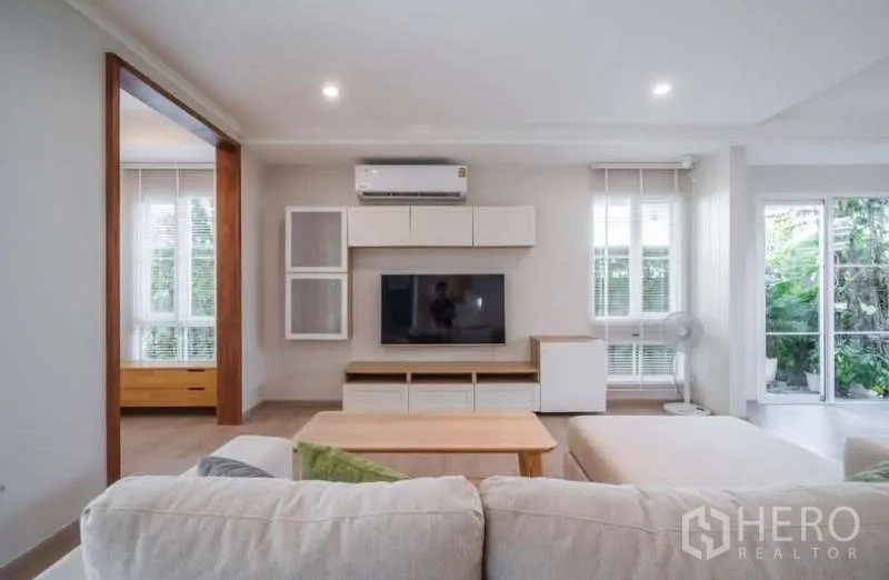 Detached House for rent in Prawet, Bangkok - Open living area view showing TV built-ins and sliding doors to the garden.