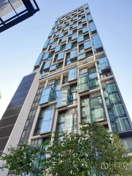 Condominium for rent in Pathum Wan, Bangkok - Modern glass high-rise facade of 28 Chidlom condominium against a blue sky.