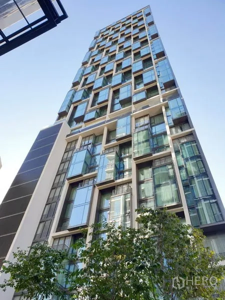 Condominium for rent in Pathum Wan, Bangkok - Modern glass high-rise facade of 28 Chidlom condominium against a blue sky.