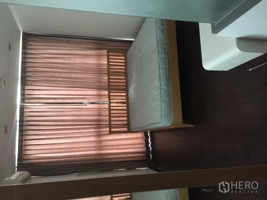 Condominium for rent in Ratchathewi, Bangkok - Bright bedroom with wooden bed frame, floor-to-ceiling curtains and dark wood flooring in a Bangkok condo.