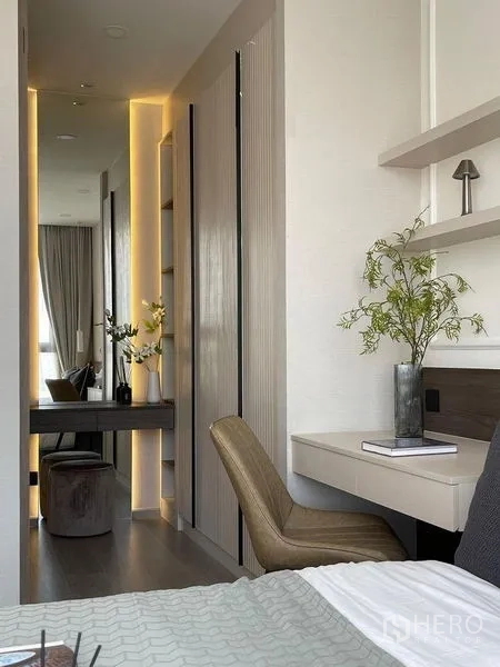 公寓 出租在Pathum Wan, Bangkok - 卧室工作区，悬空书桌、座椅与带灯光的衣柜走道。