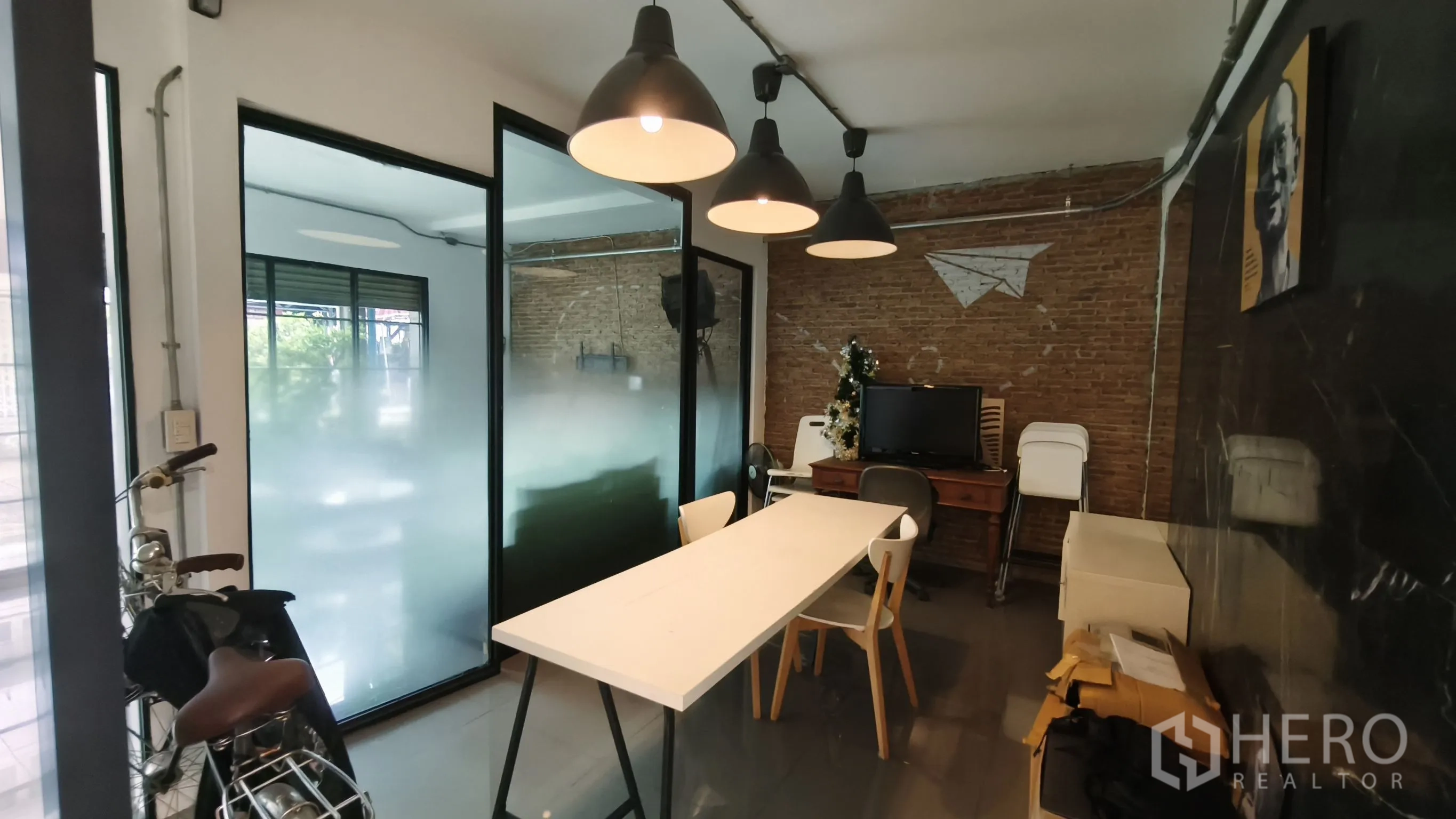 店屋 for rent in Khlong Toei, Bangkok - 工业风工作区，设长桌、吊灯、磨砂玻璃隔断与裸砖墙。