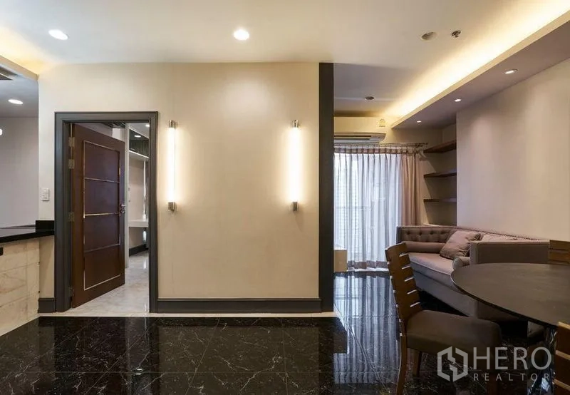 Condominium for sale in Ratchathewi, Bangkok - Cozy lounge with sofa, TV wall and sheer curtains opening to a balcony in a Bangkok condo.