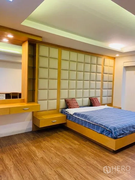 Condominium for rent in Watthana, Bangkok - Master bedroom with a padded feature headboard, built-in side shelves and warm wood flooring.
