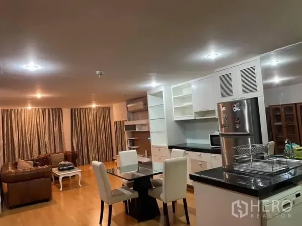 Condominium for rent or sale in Watthana, Bangkok - Integrated living, dining and white kitchen with black countertops, dining table, and stainless refrigerator.