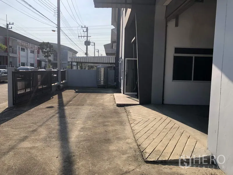工厂 出租在Lam Luk Ka, Pathum Thani - 建筑侧院通道连接装卸区与滑动大门，适合卡车进出。