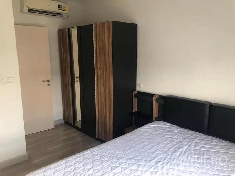 Townhouse for rent in Saphan Sung, Bangkok - Secondary bedroom with bed, mirrored wardrobe and wall-mounted air-conditioner.