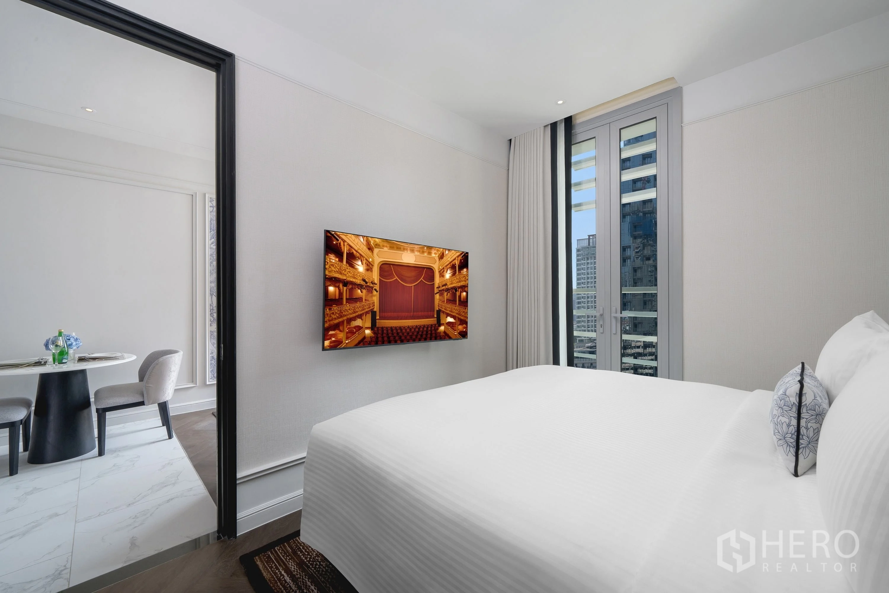 Condominium for rent in Khlong Toei, Bangkok - Bright bedroom with large bed, wall-mounted TV, and city view window.