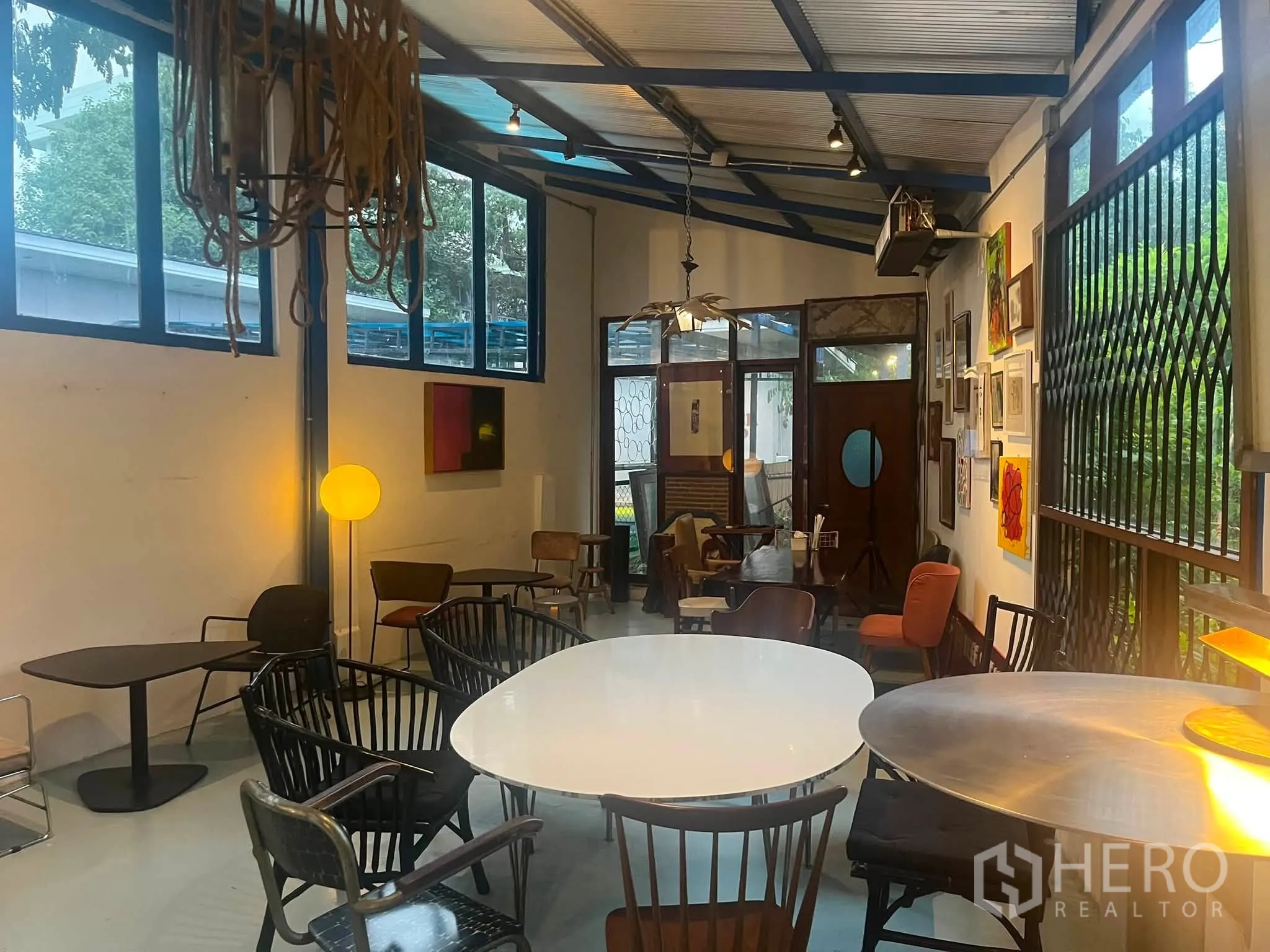 零售空间 for rent in Watthana, Bangkok - 明亮的室内就座区，吊灯照明，白墙挂满艺术画作。