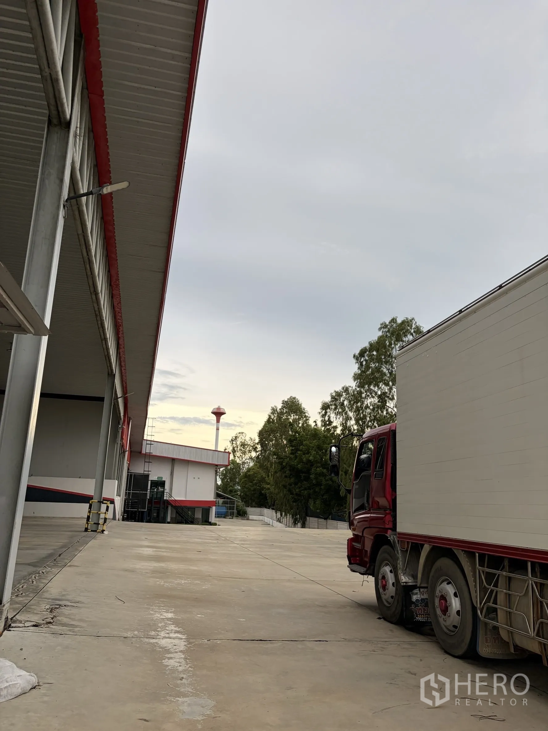 Factory for sale in Mueang Nakhon Pathom, Nakhon Pathom - Side view of loading area and red truck along wide access road.
