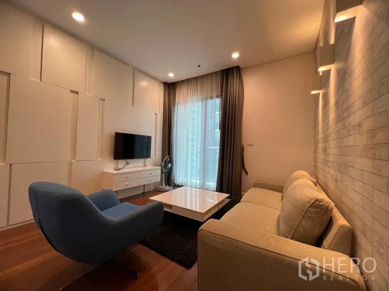 公寓 出租在Khlong Toei, Bangkok - 温馨客厅，配沙发、单椅、壁挂电视及通往阳台的推拉门。