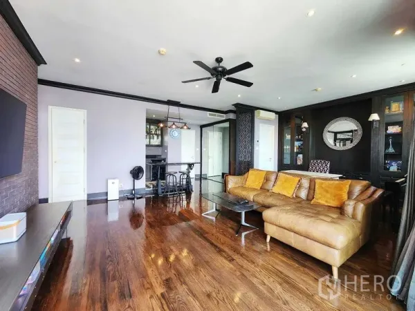 Condominium for sale in Khlong Toei, Bangkok - Spacious living room connecting to kitchen, showcasing glossy wood flooring.