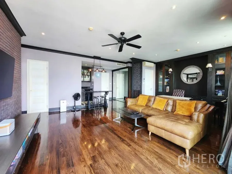 Condominium for sale in Khlong Toei, Bangkok - Spacious living room connecting to kitchen, showcasing glossy wood flooring.