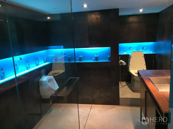 公寓 出租在Khlong Toei, Bangkok - 现代浴室，深色瓷砖、玻璃隔断与蓝色灯带壁龛