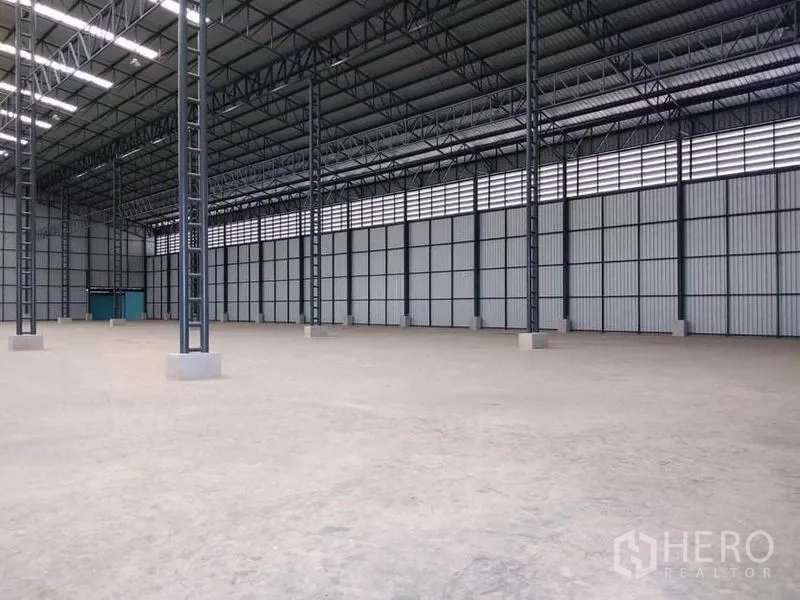 工厂 出租在Mueang Samut Prakan, Samut Prakan - 开放式生产空间，混凝土地面，金属夹芯墙体与青色服务门。