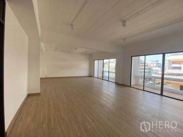 Office Space for rent in Watthana, Bangkok - Wide view of the office interior with multiple sliding doors to a balcony and abundant natural light.