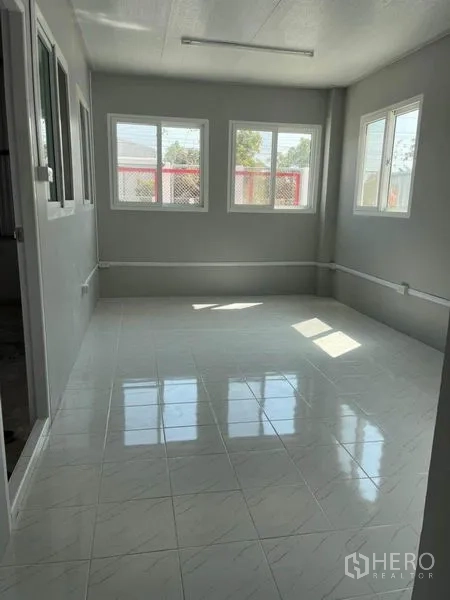 Warehouse for rent in Nonthaburi - Street-facing facade of a standalone warehouse with wide gate and large concrete apron.