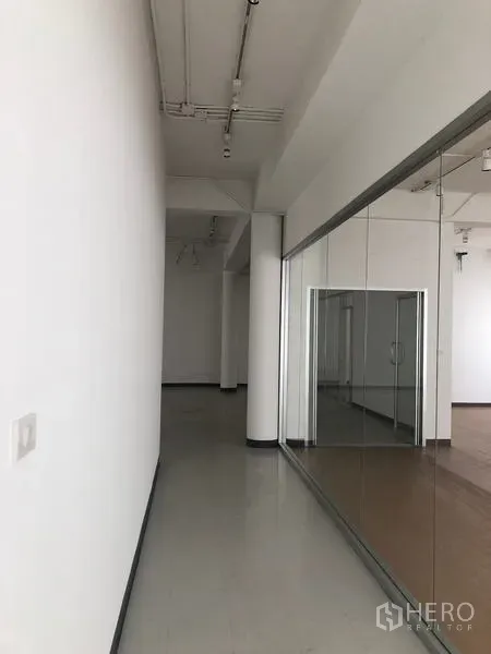 สำนักงาน ให้เช่าในBang Rak, Bangkok - โถงทางเดินสีขาว เพดานสูง กั้นห้องด้วยกระจก เชื่อมสู่พื้นที่พื้นลายไม้