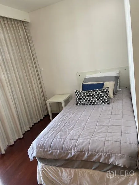Condominium for rent in Pathum Wan, Bangkok - Compact guest bedroom with single bed and floor-to-ceiling curtains.
