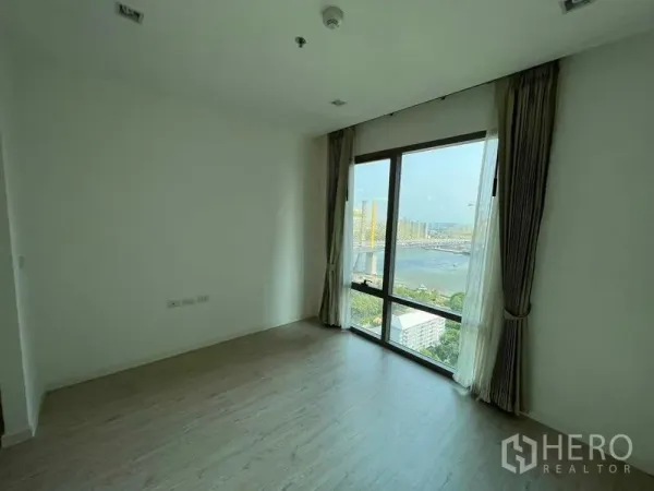 Condominium for sale - Bright bedroom with floor-to-ceiling window showcasing a wide river and city view.