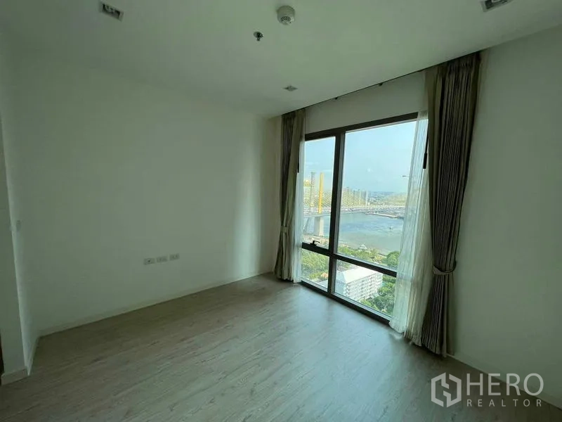 Condominium for sale - Bright bedroom with floor-to-ceiling window showcasing a wide river and city view.
