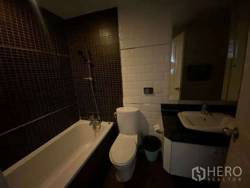 公寓 出租在Khlong Toei, Bangkok - 深色系浴室，浴缸带淋浴、坐便与台盆。