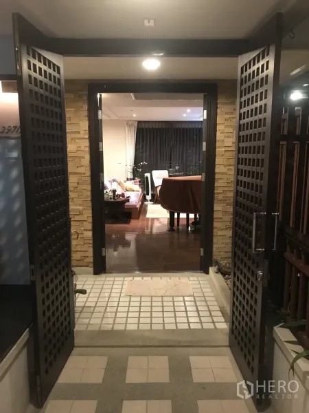 Condominium for sale in Yan Nawa, Bangkok - Secure entry with lattice double doors opening to a warm living area with wooden floors.