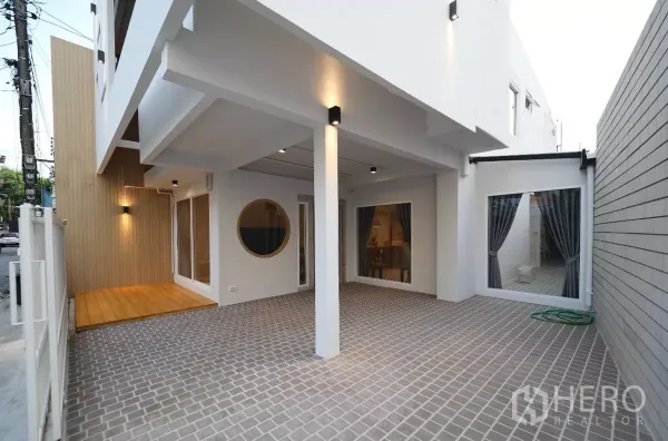 联排别墅 出租或出售在Watthana, Bangkok - 有顶车位与铺砖庭院，木质细节和落地窗相连。