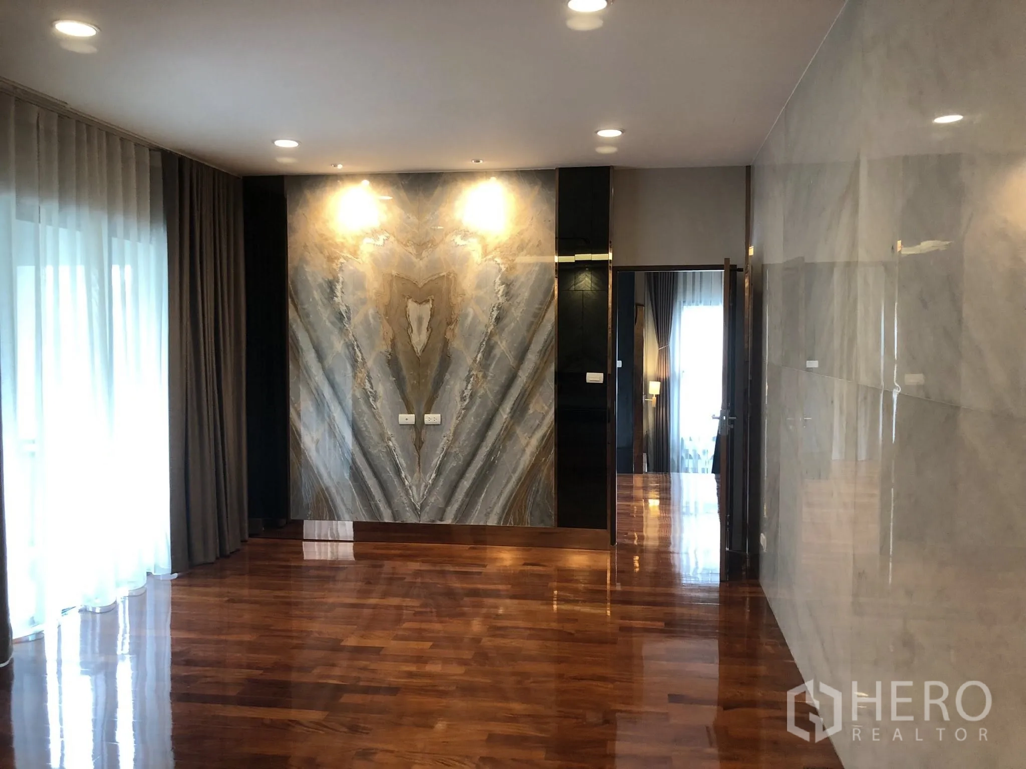 Detached House for rent in Bang Khae, Bangkok - Elegant living area with statement stone feature wall and glossy timber flooring.