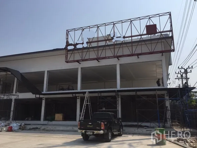 Warehouse for rent in Bang Kapi, Bangkok - Front facade close-up of the warehouse showing a rooftop billboard frame, high ceilings and parking space.