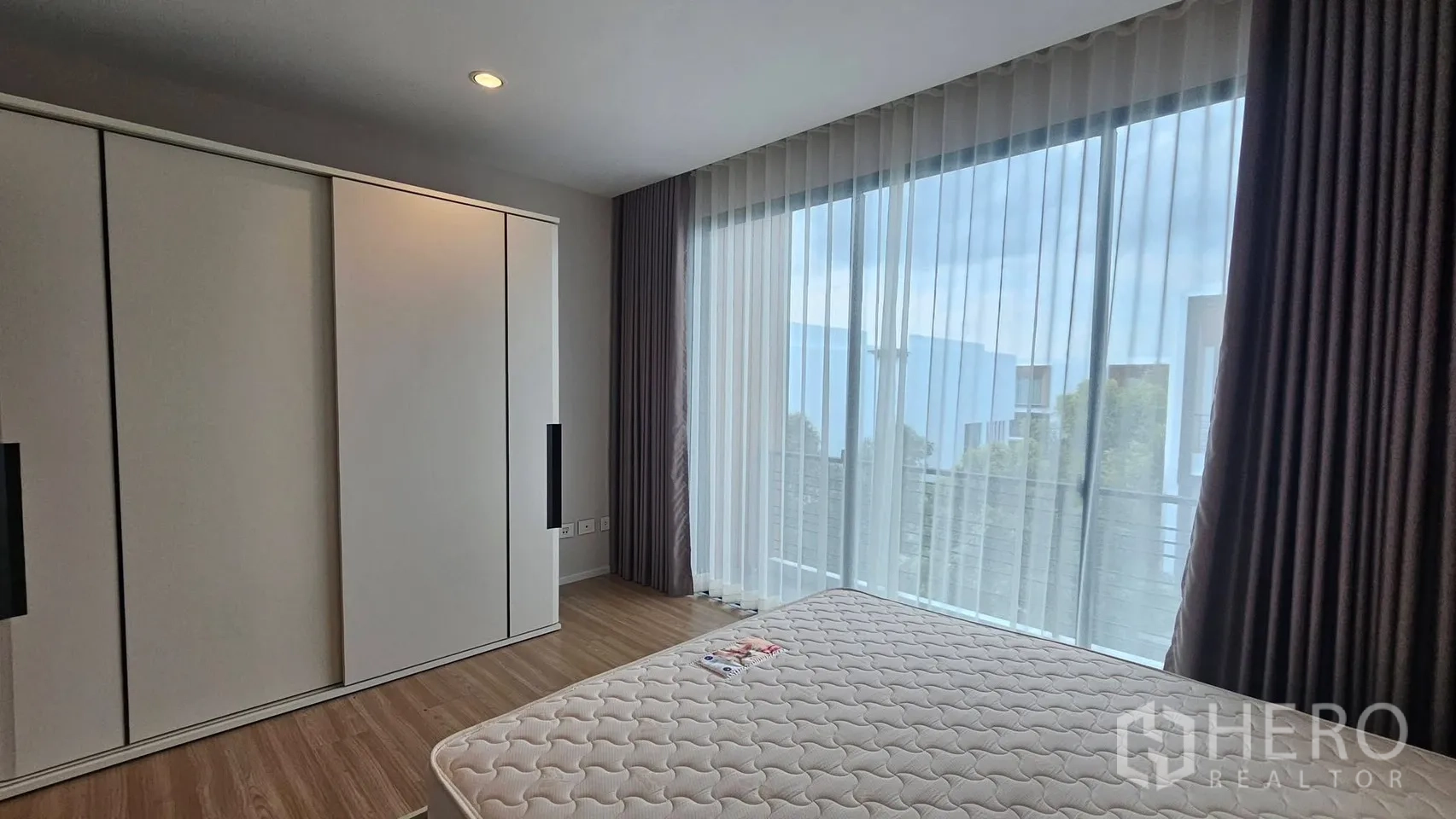 Townhouse for rent in Saphan Sung, Bangkok - Bright bedroom with floor-to-ceiling windows, sheer curtains, and a built-in wardrobe.