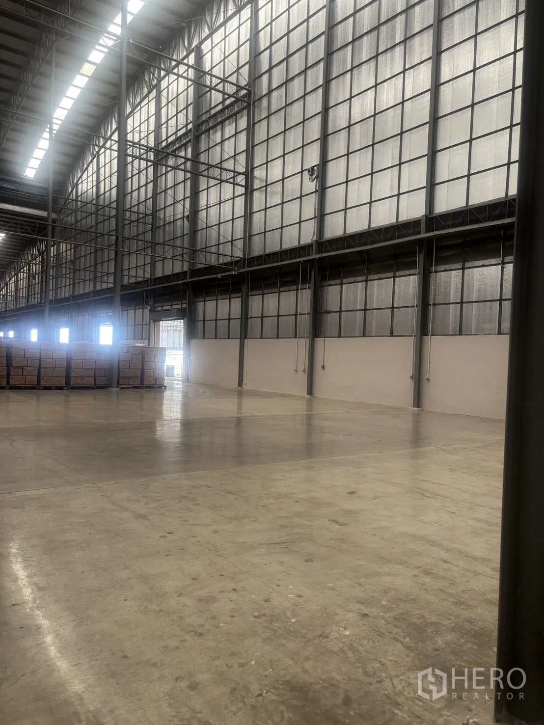 Warehouse for rent in Mueang Samut Sakhon, Samut Sakhon - Wide open warehouse aisle with translucent panels, polished concrete floor and stacked pallets.