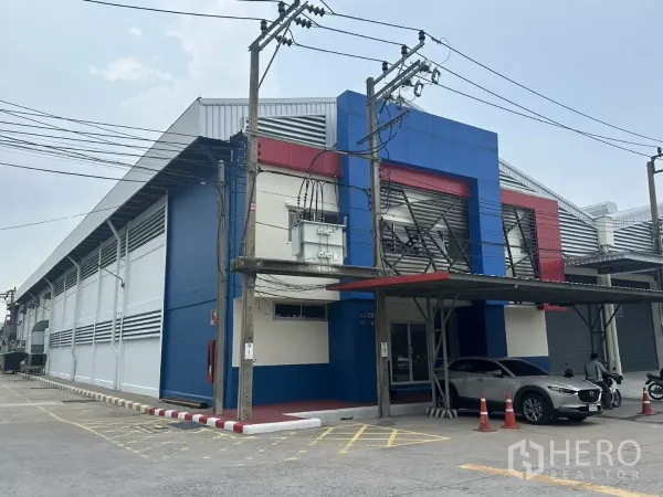 Factory for rent in Bang Phli, Samut Prakan - Side elevation of the warehouse building with canopy parking and electrical transformer.
