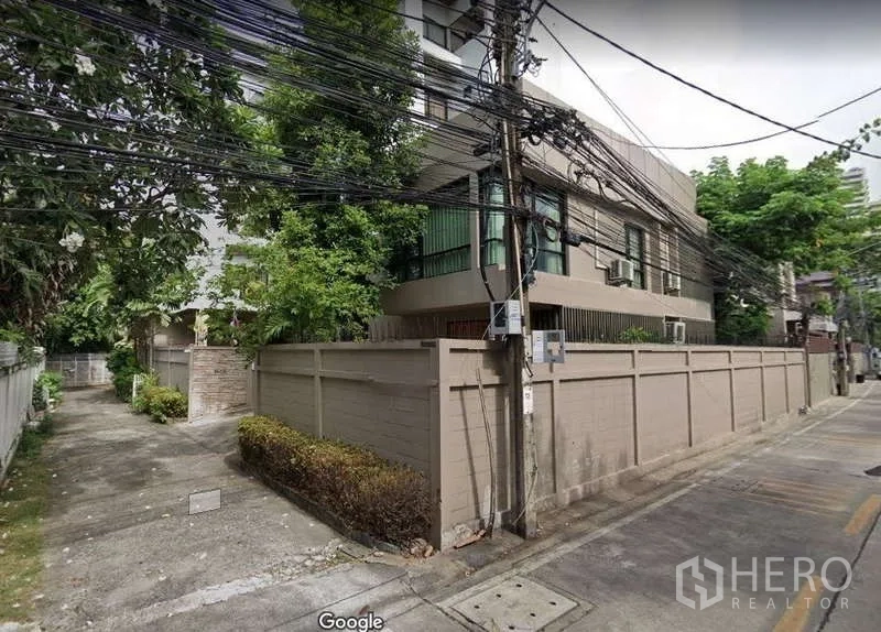 Detached House for rent - Street corner view of a walled detached house with mature trees on a quiet lane in Bangkok.