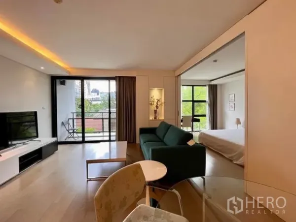 Condominium for rent in Watthana, Bangkok - Living area with sliding glass doors to the bedroom, balcony seating, and warm cove lighting.