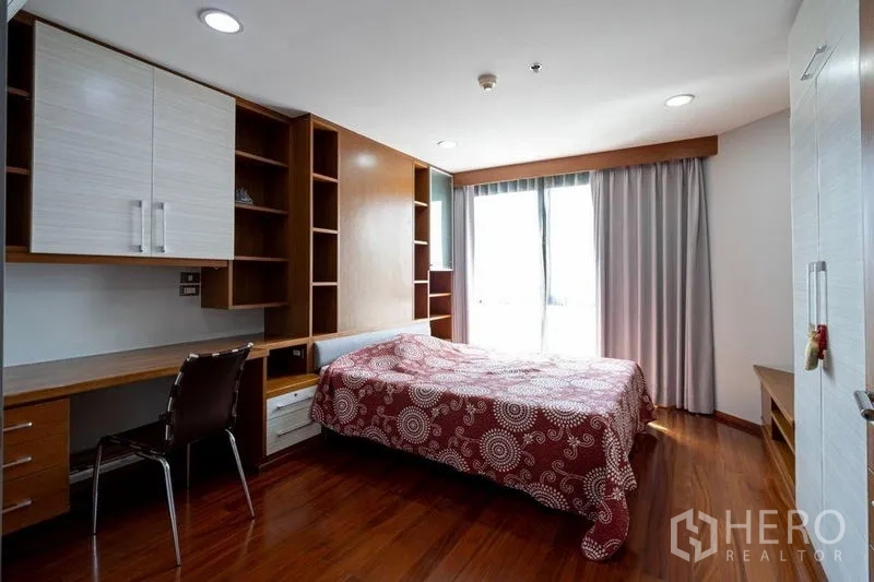 公寓 出售在Watthana, Bangkok - 卧室带书桌与壁柜，木地板及带窗帘的双人床位。