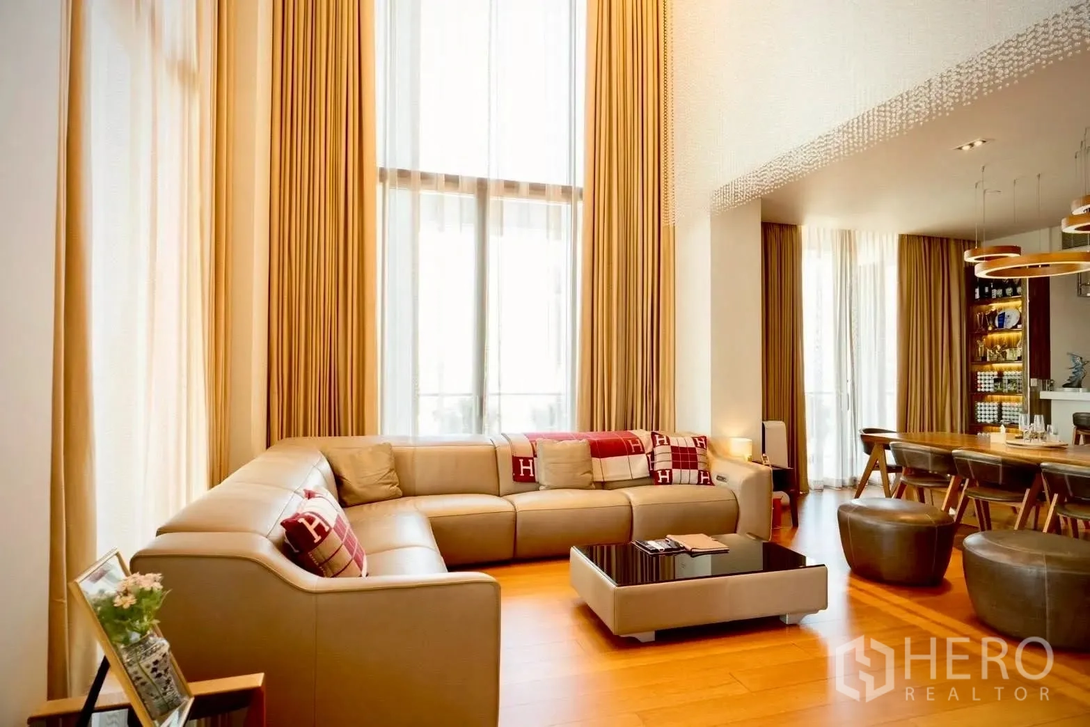 Condominium for sale in Sathon, Bangkok - Sunny lounge with tall curtains, sectional sofa, and adjoining dining zone.