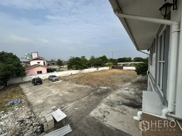 สำนักงานที่บ้าน ให้เช่า - มุมมองชั้นบนเห็นลานจอดรถคอนกรีตและรถยนต์ภายในรั้ว.