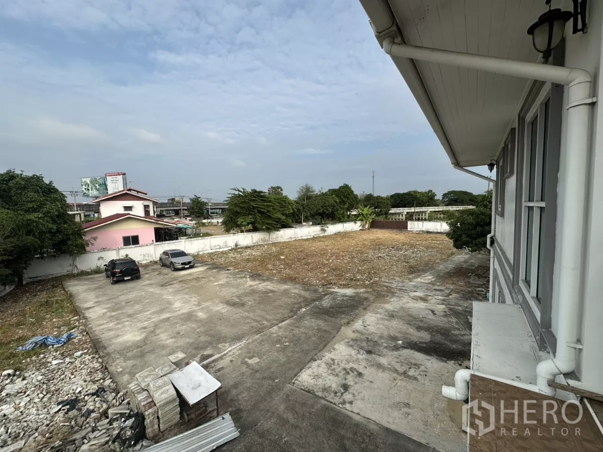 สำนักงานที่บ้าน ให้เช่า - มุมมองชั้นบนเห็นลานจอดรถคอนกรีตและรถยนต์ภายในรั้ว.