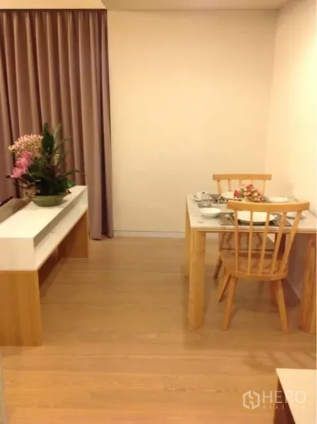 Condominium for rent or sale in Watthana, Bangkok - Cozy dining nook with white table, wooden chair and floor-to-ceiling curtains