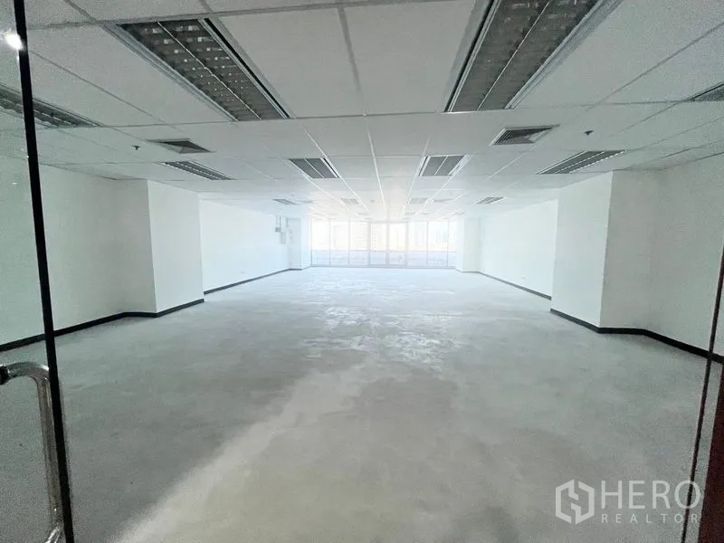 Office Space for rent in Watthana, Bangkok - Spacious open-plan office interior with suspended grid ceiling, fluorescent lighting, and wide rear windows bringing in natural light.