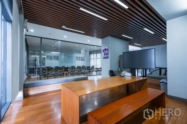 Office Space for rent - Open lounge with wooden bench, TV, and glass-walled conference room.