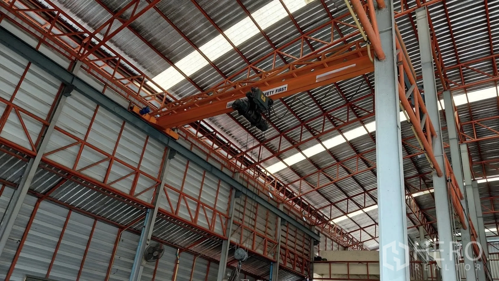 Warehouse for rent in Bang Phli, Samut Prakan - Interior of steel-frame warehouse showing high roof with skylight panels and an overhead bridge crane.