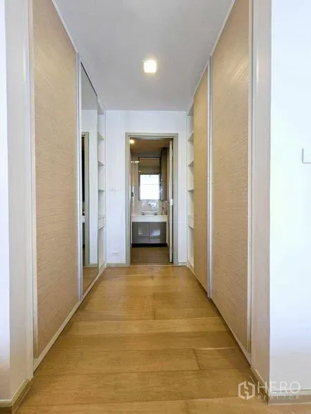 Condominium for rent - Hallway with built-in wardrobes and mirrors leading to a sleek bathroom.